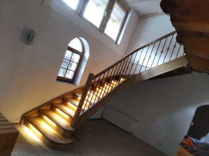 Dřevěné interiérové schodiště s kulatou bočnicí a osvětlením